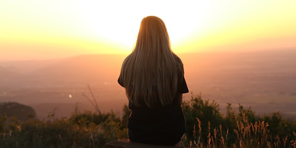 A woman sitting and watching the sunrise