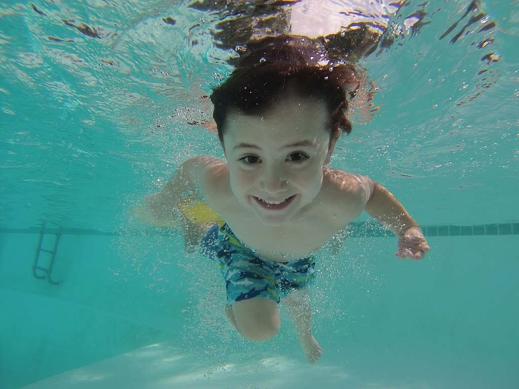 A boy is swimming in the water happily