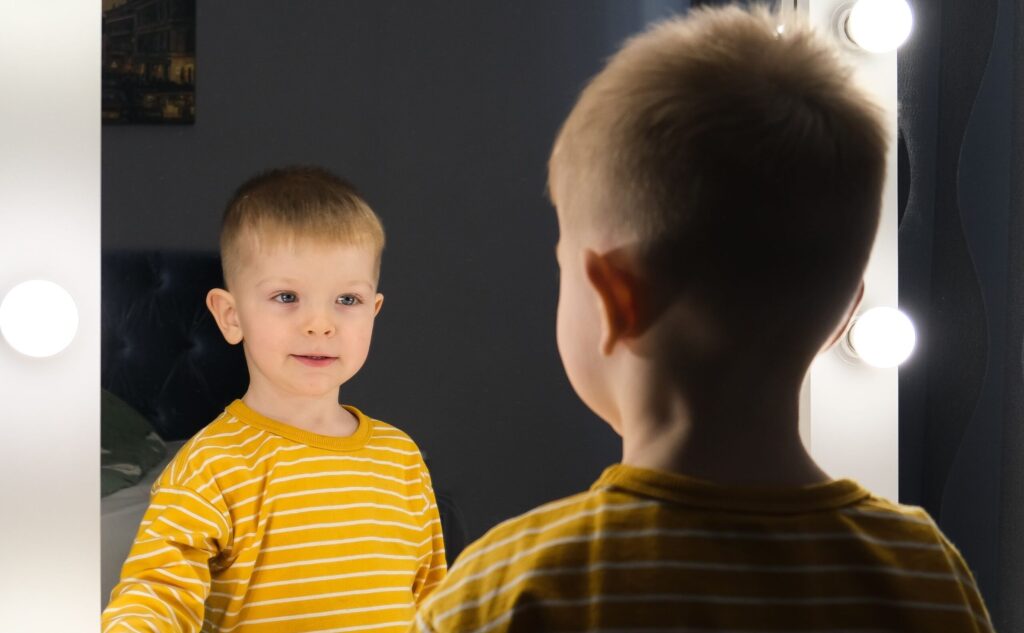 A boy seeing his image on mirror