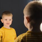 A boy seeing his image on mirror